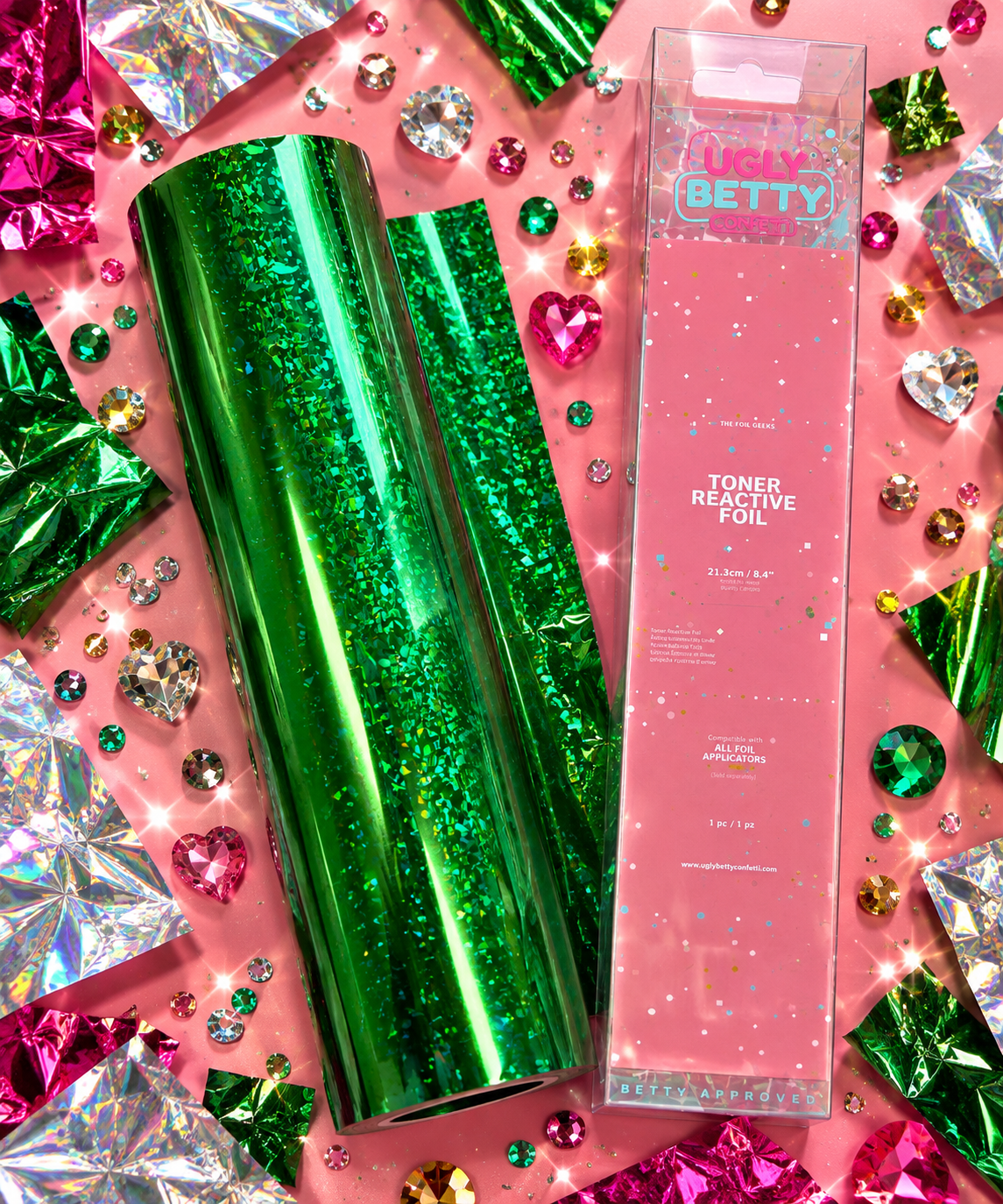 Emerald City green crackle holographic toner reactive foil roll with Ugly Betty Confetti packaging, flat lay on pink
