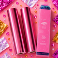 Two rolls of pink toner reactive foil and a box labeled 'Ugly Betty' on a pink background with confetti.