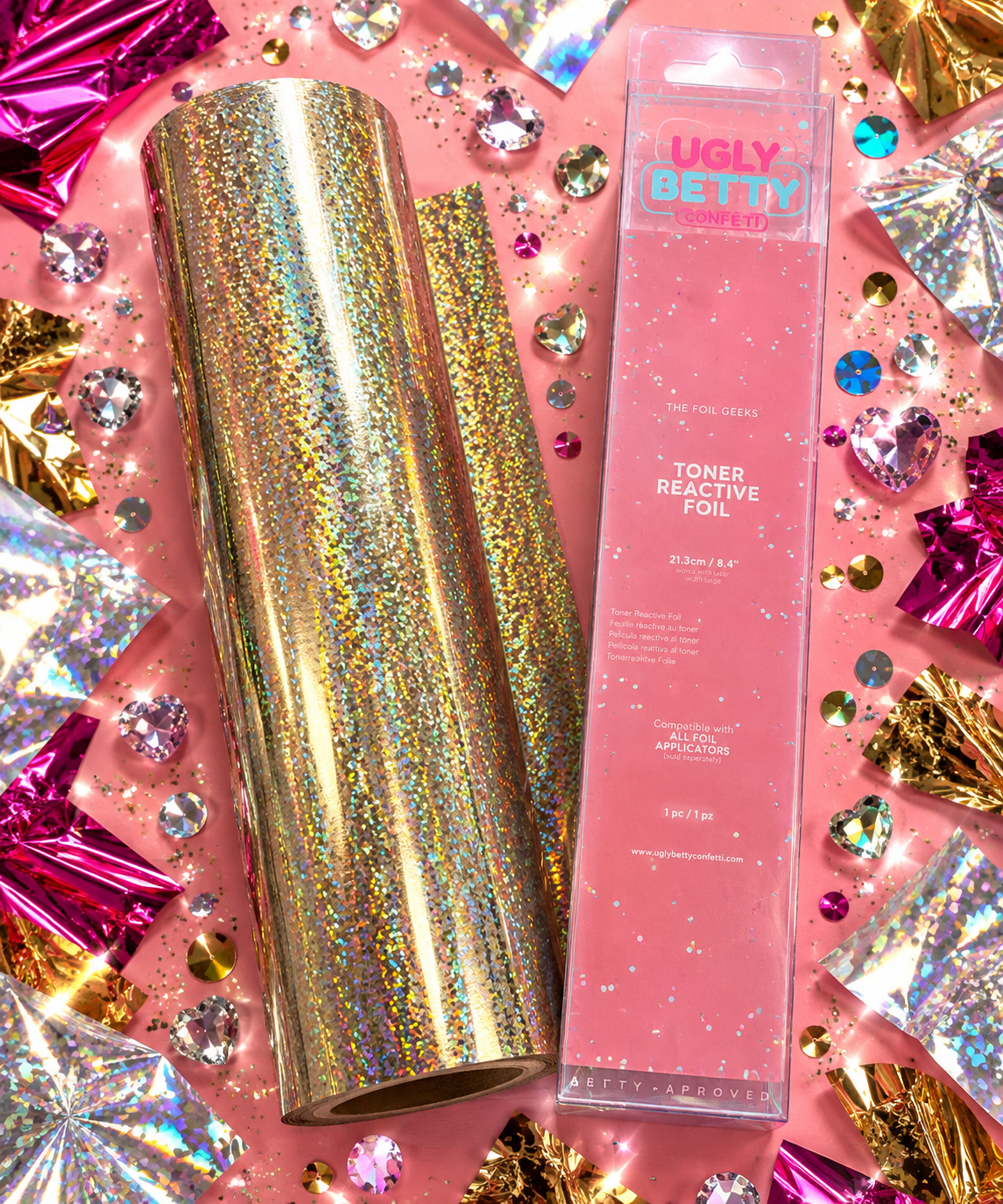 Gold Digger gold laser sand holographic toner reactive foil roll with Ugly Betty Confetti packaging, flat lay on pink