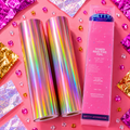 Two rolls of colorful toner reactive foil and its packaging on a pink background with decorative elements.